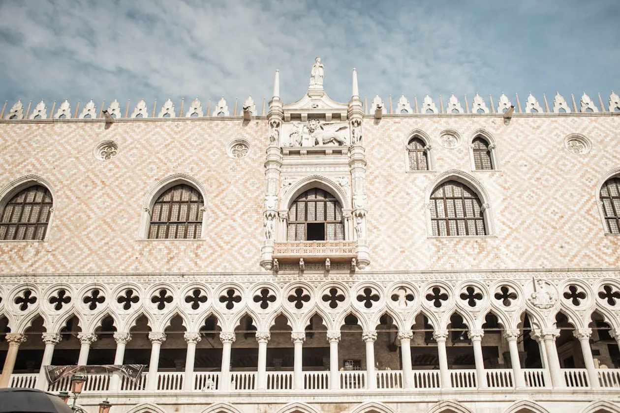 Gothic facade of the Doge's Palace on St. Mark's Square, Venice — pink marble and white stone arches