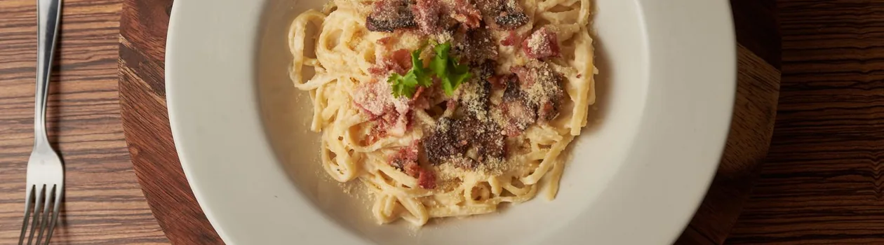 Plate of spaghetti carbonara on a wooden table in Rome