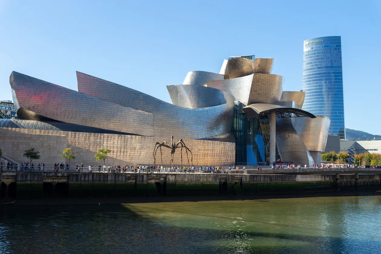 The Guggenheim Museum Bilbao from across the Nervión, with Louise Bourgeois's Maman spider on the riverside walkway and the Iberdrola Tower behind