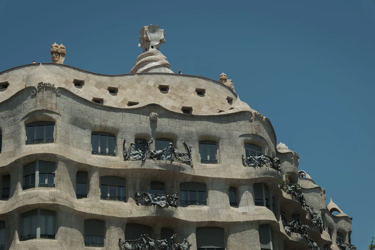 Casa Milà's chamfered corner on Passeig de Gràcia, wavy stone façade with wrought-iron balconies and the rooftop stairwell towers above