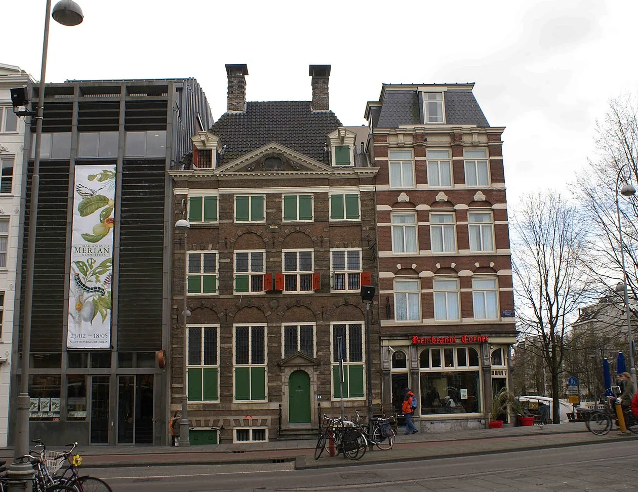 Rembrandt's house on Jodenbreestraat in Amsterdam, a brick facade with green shutters, a green front door and the date 1606, between the museum's modern wing and the Rembrandt Corner café